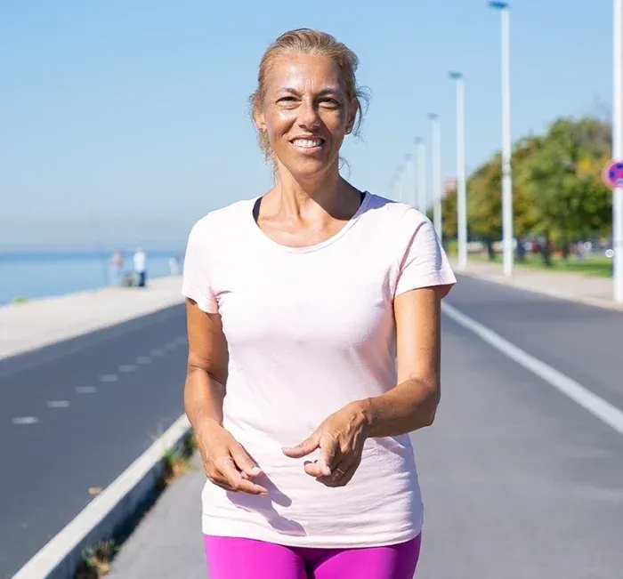 A smiling woman walking on a seaside promenade